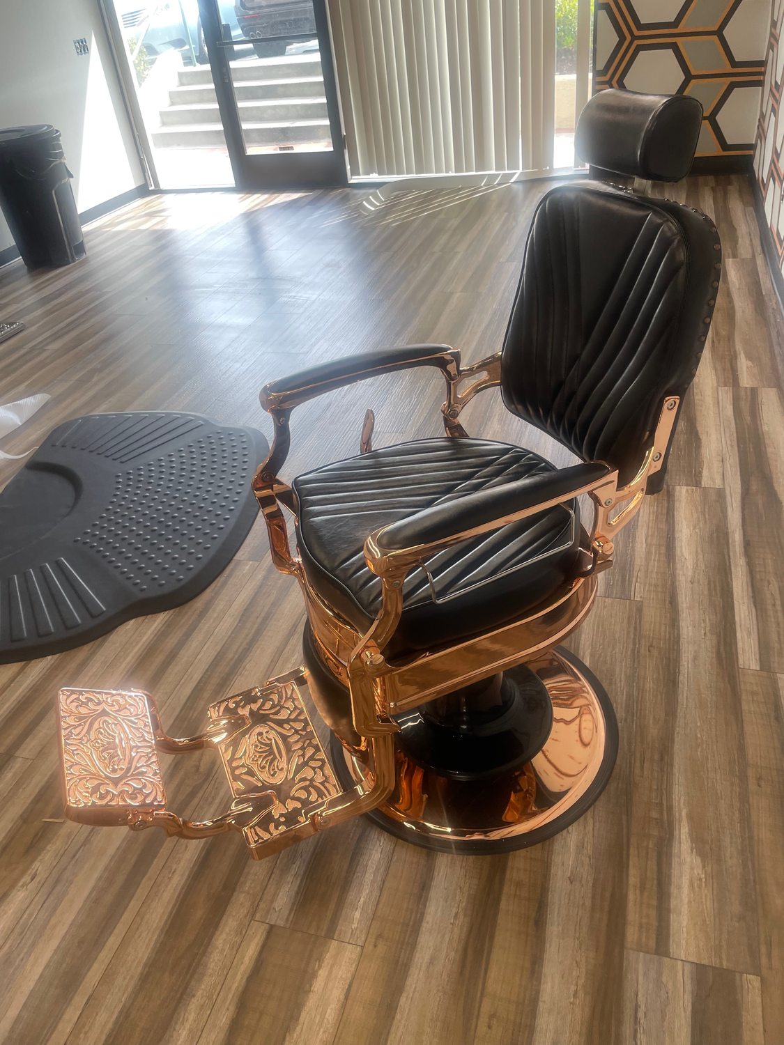 Rose-gold barber chair in morning light by the storefront window